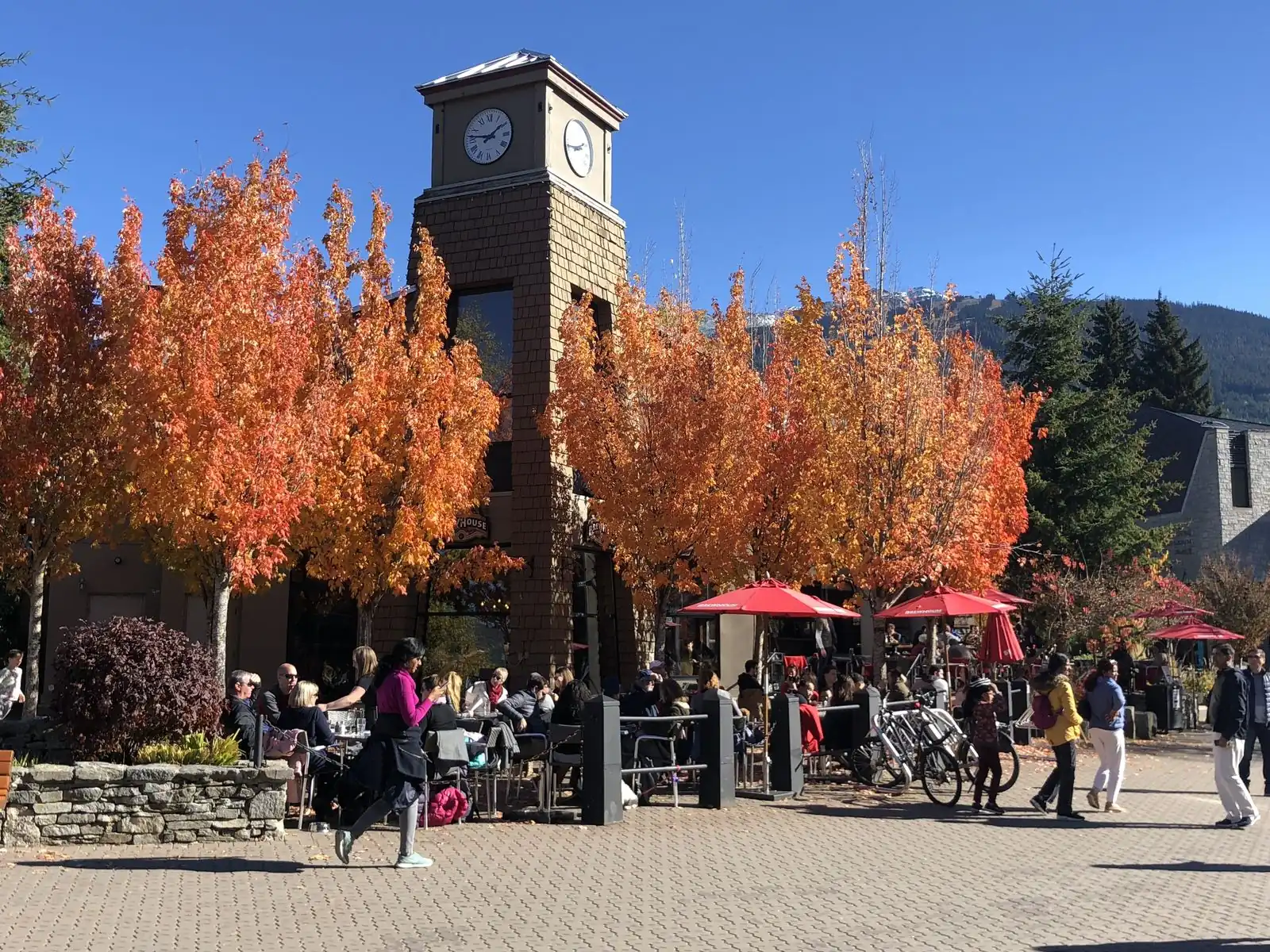 Torre do relógio na Vila de Whistler, com folhas de outono e mesas ao ar livre
